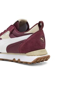Baskets Puma bordeaux et beige montrant l'arrière et le côté, avec des matériaux en daim et en mesh, une bande blanche et une semelle en gomme texturée.
