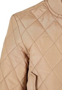 Beige quiltad bomberjacka med ribbad krage och diagonal sömnadsdesign, tillverkad av ett mjukt och lätt tyg.