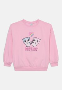 Pink sweatshirt featuring two cartoon cats holding a heart with a rainbow. Text below reads "BESTIES." Material appears soft with ribbed cuffs.