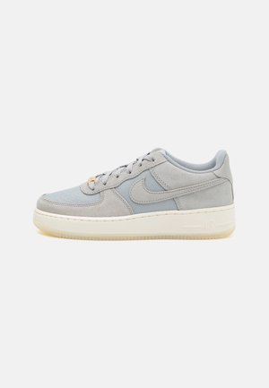 Baskets basses grises Nike Air Force 1 avec panneaux en daim et mesh, semelle intermédiaire blanche et fermeture à lacets sur fond clair.