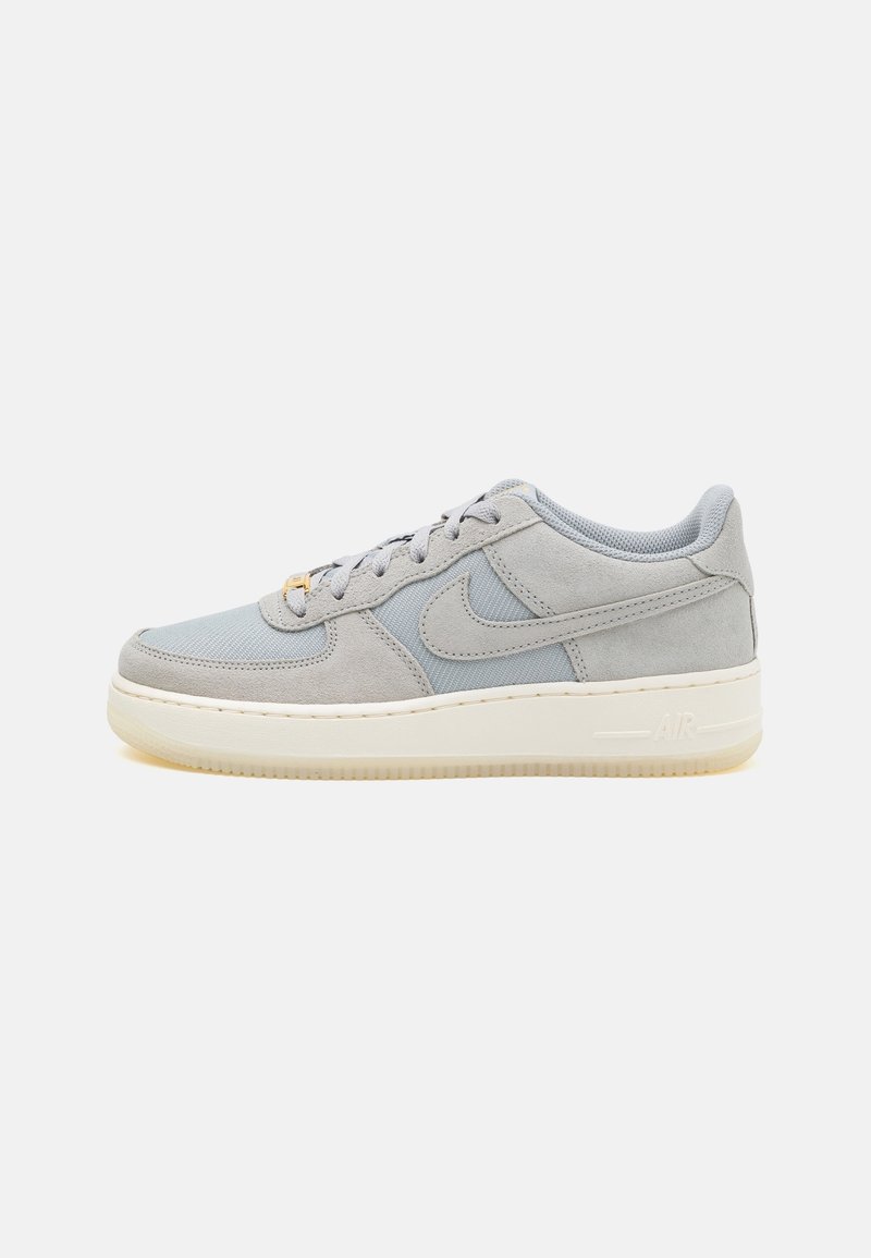 Baskets basses grises Nike Air Force 1 avec panneaux en daim et mesh, semelle intermédiaire blanche et fermeture à lacets sur fond clair.