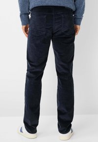 Marineblauwe corduroy broek met een slim fit, voorzien van twee achterzakken en een ribbelstructuur, gecombineerd met witte sneakers.