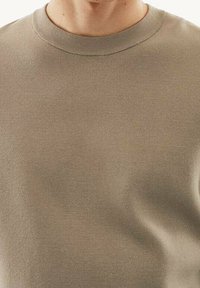 Béžová bavlněná mikina s kulatým výstřihem a ribbed lemem. Hladký materiál, jednoduchý design, bez vzorů nebo ozdob.