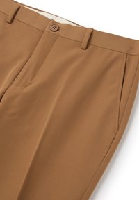 Pantalones marrones a medida elaborados con una tela suave, que presentan un cierre de botón, bolsillos delanteros y un diseño limpio y minimalista.