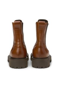 Braune Lederstiefeletten mit elastischen Seiteneinsätzen, runden Zehen und dicken braunen Gummisohlen mit einem strukturierten Profil.