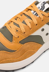 Sneakers med en kombinasjon av oransje semsket skinn og olivengrønn mesh, med teksturerte skolisser, en hvit logoakcent, og et lagdelt design.