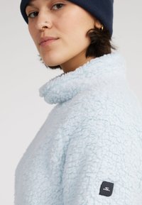 Lichtblauwe fleece pullover met een hoge kraag, gestructureerd oppervlak en een klein zwart O'Neill logo-opdruk op de mouw.