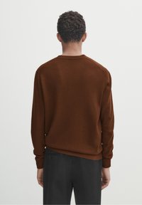 Bruine gebreide trui met een ronde halslijn en rib gebreide manchetten. Soepele textuur, aansluitend ontwerp en minimalistische stijl. Draagbaar met een donkere broek.