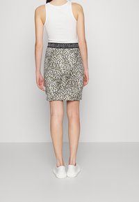 Leopardprint blyantskirt med tætsiddende design, beige og sorte farver, elastisk talje med logo-detalje og glat tekstur.