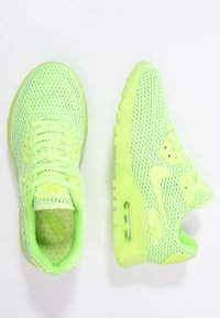 Pair of neon green mesh Nike Air Max sneakers, one showing top view and the other a side profile on a white background.