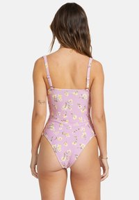 Maillot de bain une pièce en violet clair avec imprimé floral, bretelles réglables et jambes échancrées. Fabriqué en tissu côtelé pour une texture.