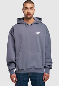Grå hættetrøje med en frontlomme, der har et hvidt trykt design af en person, der holder balloner. Blødt stof og afslappet pasform.