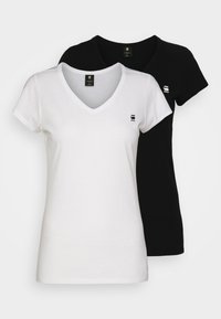 Twee V-hals t-shirts in zwart en wit. Zacht katoenen materiaal, korte mouwen, met een klein logo op de linkerkant van de borst van elk shirt.