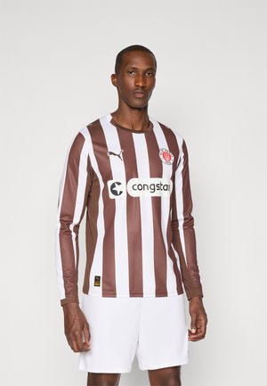Langærmet fodboldtrøje med brune og hvide lodrette striber, med et logo og sponsor i midten, parret med hvide shorts.