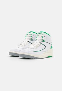 Bílé kožené vysoké sneakers s zelenými akcenty. Mají kulaté tkaničky, perforované detaily a šedou gumovou podrážku.