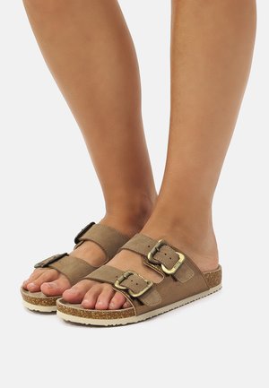 Sandalias de ante marrón tipo slide con dos hebillas ajustables, suela de corcho texturizada y diseño plano para mayor comodidad.