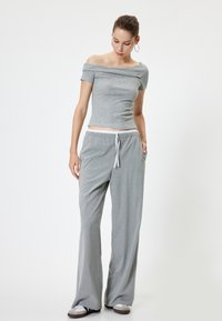 Harmaa olkaimeton pusero, jossa on lyhyet hihat ja tiukka muotoilu, yhdistettynä harmaisiin viivallisii laivastohousuihin, joissa on kiristysvyötärö.