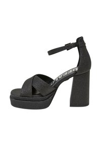 Sandalias de plataforma negras con una textura brillante, que presentan un diseño de tiras cruzadas anchas, correa al tobillo y un tacón de bloque grueso.
