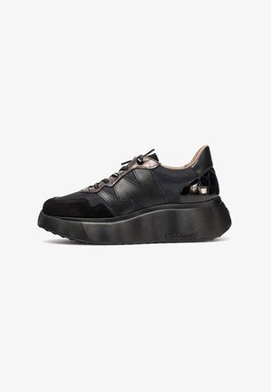 Zapatilla negra que presenta una mezcla de materiales, incluyendo cuero, ante y textil. Suela de goma chunky con diseño texturizado y acentos intrincados.
