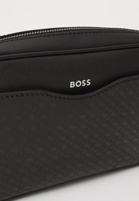 Black zippered pouch made of textured material, featuring a subtle pattern and embossed "BOSS" logo in white on the front.