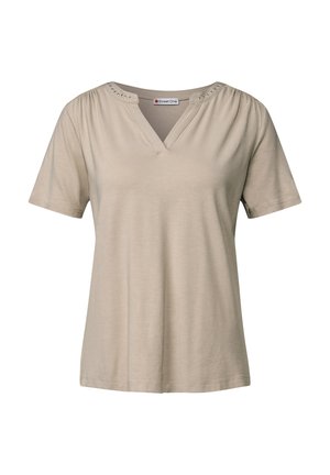 Beżowa koszulka z krótkim rękawem w serek, z zebranymi ramionami i dekoracyjnymi metalowymi ćwiekami wzdłuż dekoltu; wykonana z miękkiego, lekkiego materiału.