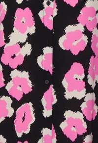Schwarzer Stoff mit weißen und lebhaft pinken Blumenmotiven. Verfügt über Druckknöpfe entlang der Vorderseite, die dem Design Textur und Kontrast verleihen.