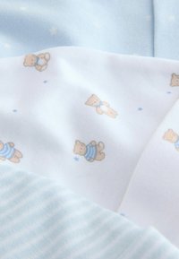 Light blue fabric features a soft texture with small teddy bear prints in blue stripes and scattered stars on a white background.