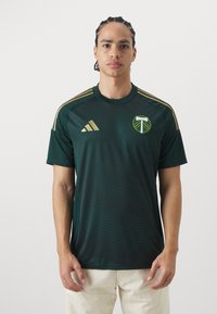 Donkergroen sportshirt met korte mouwen, voorzien van gouden accenten, een subtiele gestreepte textuur en een logo op de linkerborst.