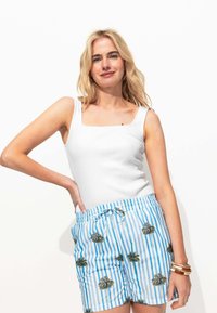 Débardeur blanc à côtes avec encolure carrée associé à un short rayé bleu et blanc avec des graphismes de palmier et une taille élastique.