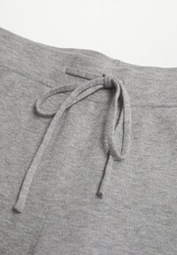 Pantaloni della tuta grigi in maglia con chiusura a coulisse, dalla texture morbida e design semplice, puntando su comfort e facilità di utilizzo.