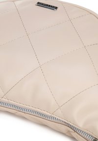 Beige gesteppte Leder-Tasche mit silbernem Reißverschluss und Nahtdetails. Verfügt über eine kleine Logo-Plakette auf der Vorderseite. Glatte Textur.