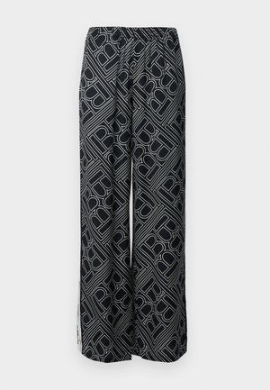 Hose mit weitem Bein aus schwarzem Stoff, der ein weißes geometrisches Muster aufweist. Elastischer Bund, fließende Form und seitliche Schlitze.