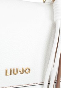 Borsa a tracolla bianca in pelle con superficie texturizzata, hardware oro e un accento beige. Presenta un logo in oro e dettagli intrecciati bianchi.