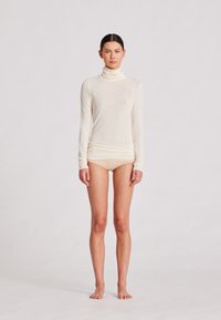 Cremfarbener, langärmliger Rollkragenpullover aus einem weichen, leichten Stoff, kombiniert mit hautfarbenen Shorts, auf einem neutralen Hintergrund präsentiert.