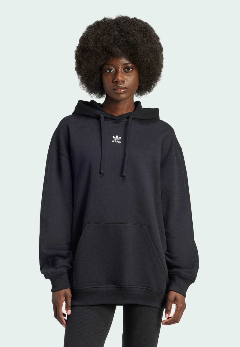 Svart oversized hettegenser laget av bomullsmiks, med en frontlomme, snøring i hetten, og hvit Adidas-logo på brystet.
