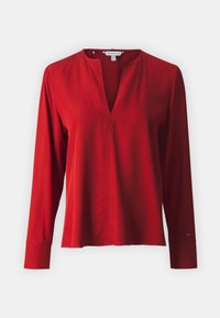 Camisa roja de manga larga hecha de tejido suave con escote en V y un ajuste relajado. Presenta puños y sutiles detalles de costura.