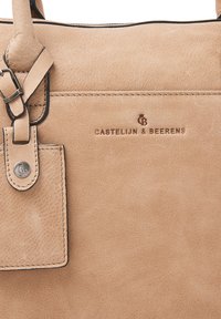 Beige leren tas met een textuur oppervlak, een toner logo, verstelbare schouderbanden en een metalen label. Minimalistisch ontwerp met subtiele stiksels.