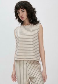 Beige mouwloos topje met dunne verticale marineblauwe strepen, met een boxy vorm en ronde hals, gemaakt van zachte stof. Gekozen in combinatie met bijpassende broek.