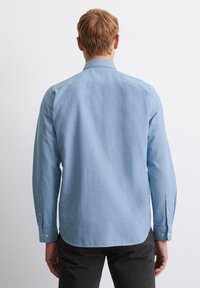 Light blue long-sleeve shirt with a collar, buttoned cuffs, and a straight back design, made of a smooth, lightweight fabric.