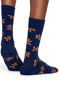 Calzini blu navy con motivo di omini di pan di zenzero, realizzati in tessuto morbido. Presentano dettagli marroni e verdi, con una fascia rossa per un tocco in più.