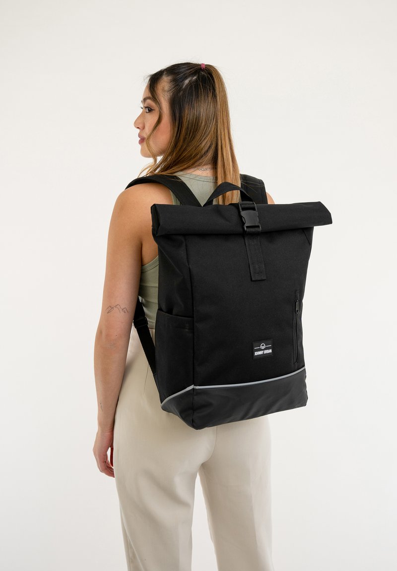 Rucsac negru cu închidere tip roll-top, buzunare din material textil și un accent reflectorizant. Dispune de curele de umăr ajustabile și detalii cu logo.