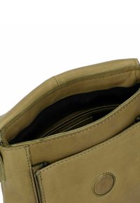Primo piano di una borsa in pelle color sabbia con l'interno in tessuto nero visibile e una zip metallica all'interno dell'apertura superiore.