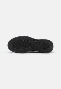 Semelle extérieure de chaussure de sport noire avec une surface en caoutchouc texturé et des rainures pour une meilleure traction et durabilité. Bords renforcés pour un soutien supplémentaire.