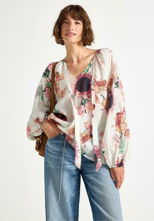 Blusa floreale in un leggero tessuto bianco, caratterizzata da colorati motivi floreali, maniche lunghe e scollatura a V con dettaglio a laccio sul davanti.