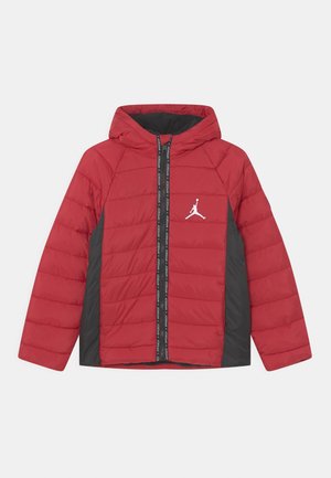 Veste matelassée à capuche rouge et noire avec fermeture éclair frontale, panneaux latéraux et logo blanc Jumpman sur la poitrine gauche.