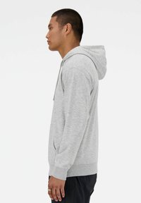 Hellgrauer Hoodie aus weichem Material, mit einer vorderen Tasche, einer Kapuze mit Kordelzug, gerippten Bündchen und einem lässigen Schnitt.