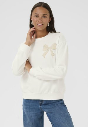 Sweatshirt blanc en matériau doux, doté d'un nœud beige clair brodé sur la poitrine gauche. Le design comprend des poignets et un ourlet côtelés.