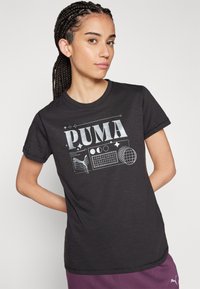 T-shirt en coton noir avec un graphique blanc portant le mot "PUMA" et des formes géométriques ; manches courtes et col rond.