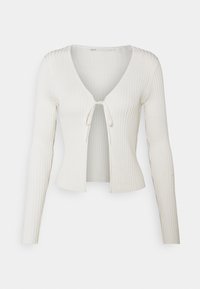 Žebrovaný bílý kardigan s dlouhými rukávy, hlubokým výstřihem do V a zavazováním vpředu. Tkanina působí měkce s jemnou texturou.