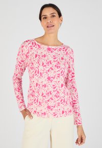 Camicia a maniche lunghe rosa con motivo floreale nei toni del rosa e crema. Collo rotondo e tessuto morbido, abbinata a pantaloni chiari.